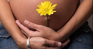 Foto donna in gravidanza che tiene nel "pancione" un fiore